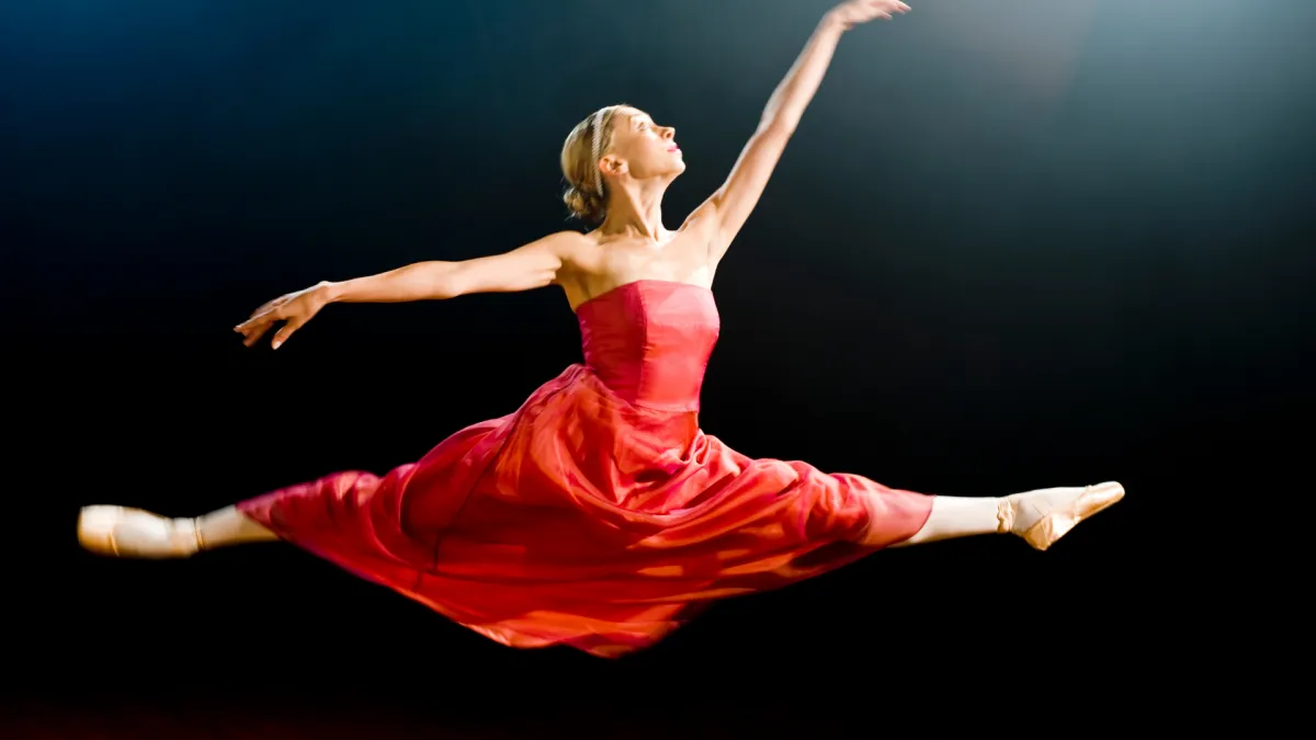 Ballet dancer in a red dress leaping mid-air, representing the CT muscle as the voice's "ballet dancer"